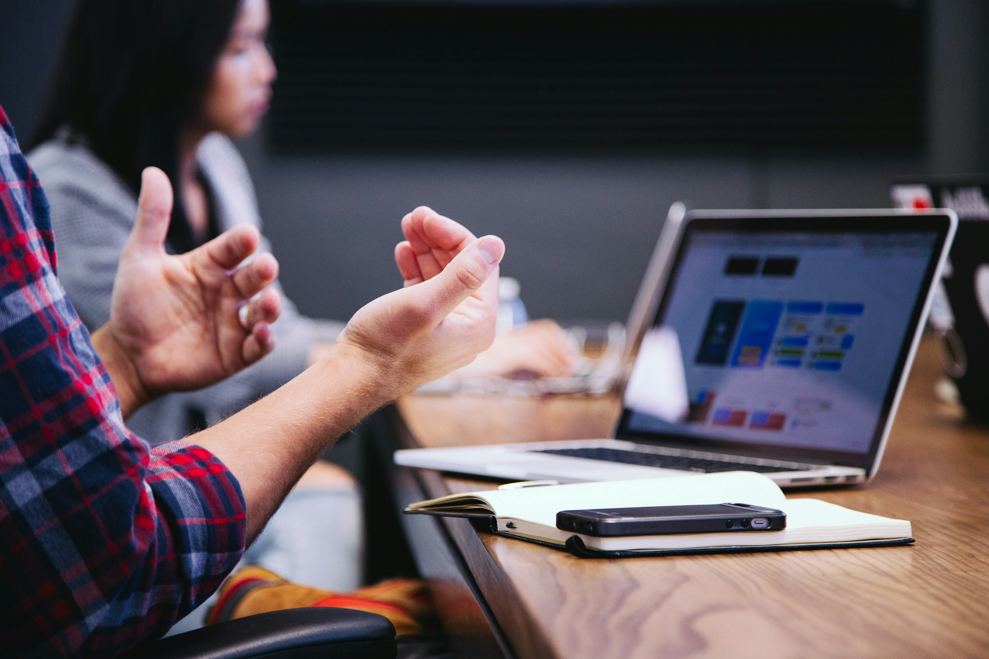 Hands in conversation beside a laptop and notebook during a meeting