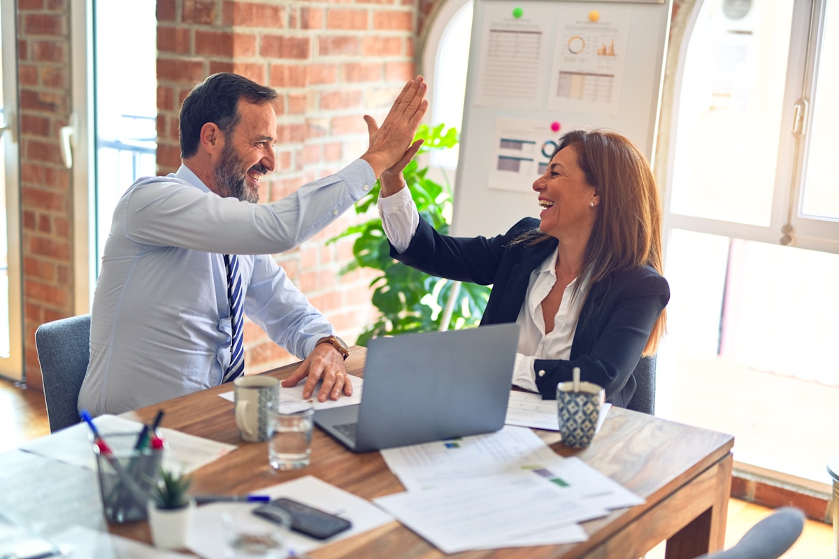 Two colleagues celebrating together at a desk